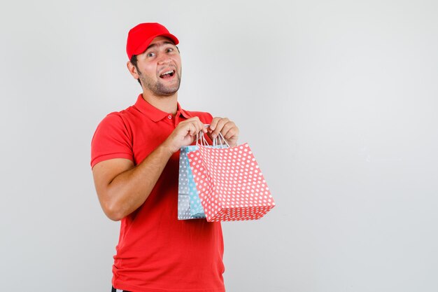 Livreur tenant des sacs en papier en t-shirt rouge