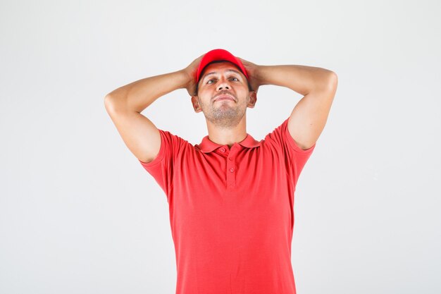 Livreur tenant la tête dans les mains en uniforme rouge et à la confusion. vue de face.