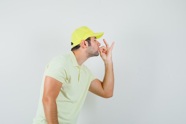 Livreur en uniforme jaune montrant un geste délicieux et ravi, vue de face.