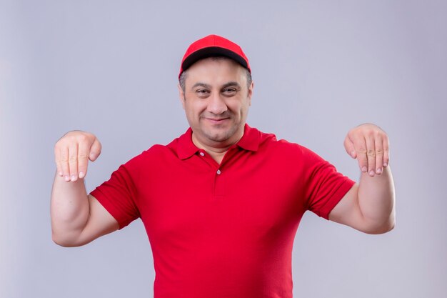 Livreur en uniforme rouge et cap gesticulant avec main souriant concept de langage corporel debout