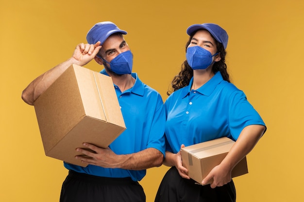 Photo gratuite livreurs masculins et féminins tenant des boîtes en carton et portant des masques médicaux