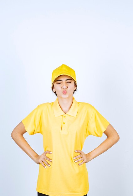 Livreuse en uniforme jaune debout et posant les mains sur les hanches.