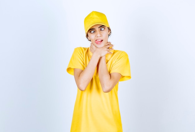 Livreuse en uniforme jaune debout et s'étranglant