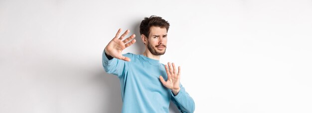 Éloignez-vous de moi jeune homme réticent reculer avec les mains tendues en geste défensif protecti