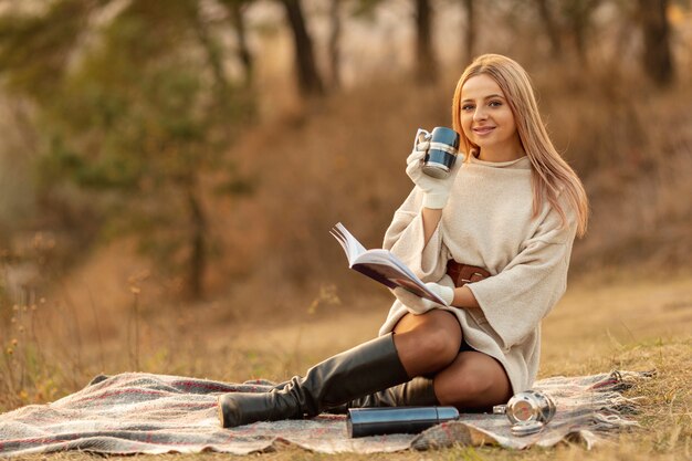 Long shot blonde femme lisant un livre