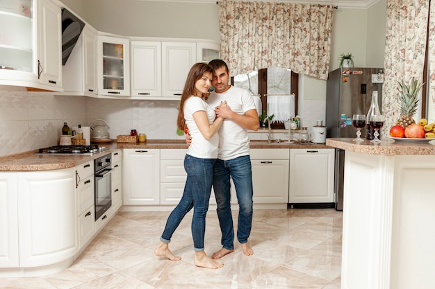 Long shot couple dancing in kitchen