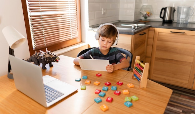 Long shot enfant fréquentant des cours d'école virtuelle