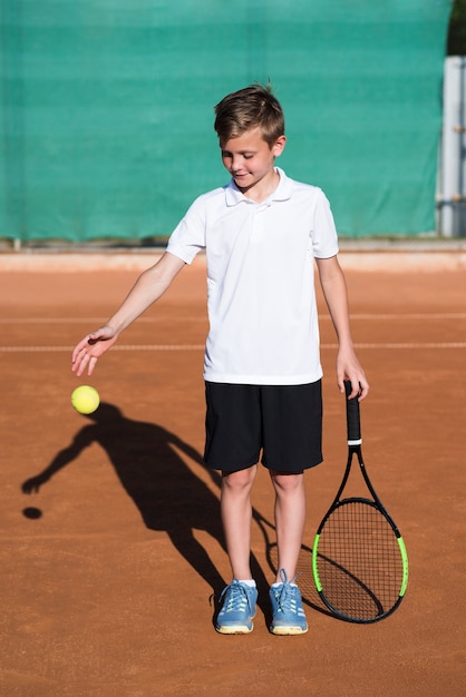 Long shot enfant jouant avec la balle de tennis