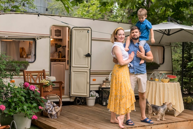 Long shot famille posant à côté de leur caravane