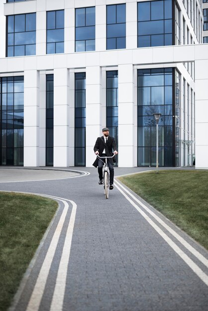 Long shot homme en costume faisant du vélo au travail