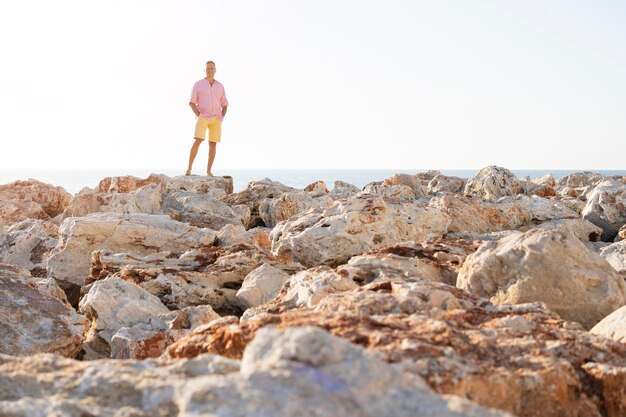 Long shot homme posant sur des rochers