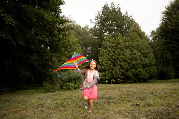 Long shot of happy girl s'amuser avec un cerf-volant