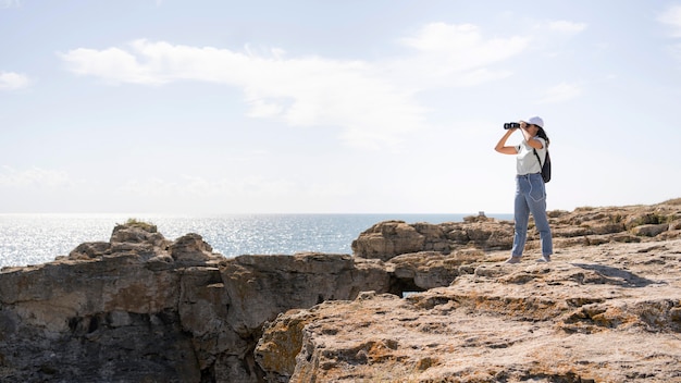 Long shot woman looking through binocular with copy space