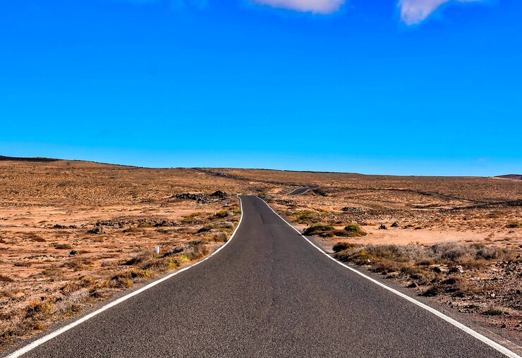 Photo gratuit longue route asphaltée dans un champ de brousse dans les îles canaries, espagne