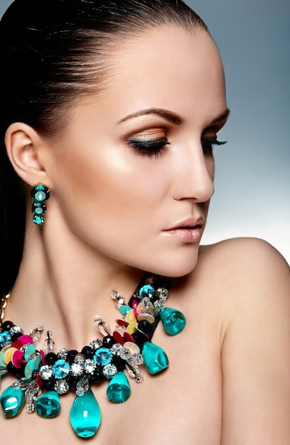 Look haute couture. Glamour closeup portrait of beautiful brunette Caucasian young woman model with Healthy hair and green accessoire jewelry