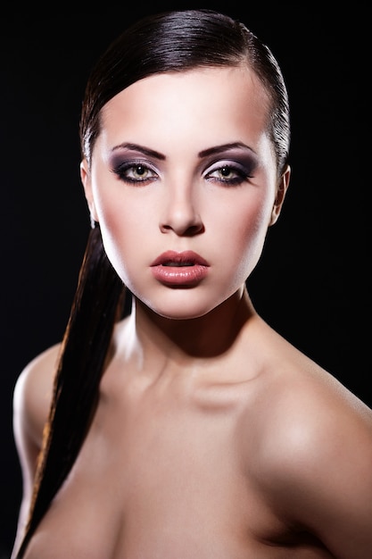 Look haute couture. portrait du modèle belle fille brune avec un maquillage lumineux et des lèvres juteuses. Une peau propre. Isolé sur noir