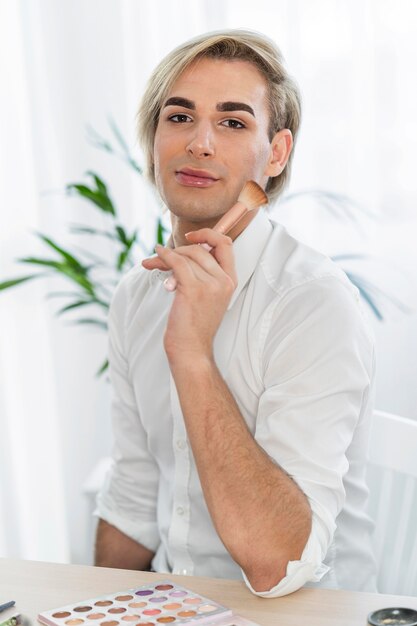 Look de maquillage masculin tenant un pinceau