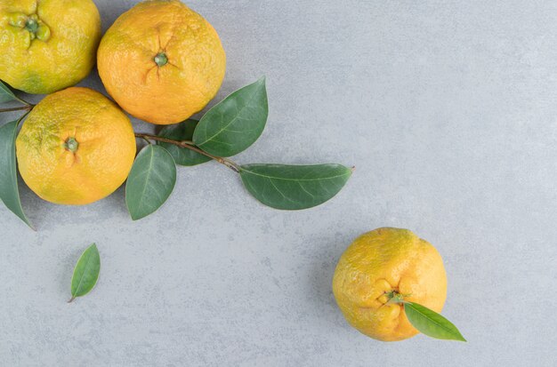 Lot de délicieuses mandarines et feuilles sur marbre.