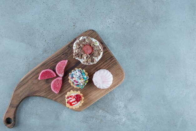 Lot de diverses pâtisseries et marmelades sur une planche de bois sur fond de marbre. Photo de haute qualité