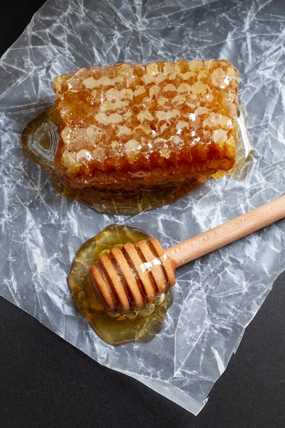 Photo gratuite louche à miel en bois avec nid d'abeille sur papier ciré