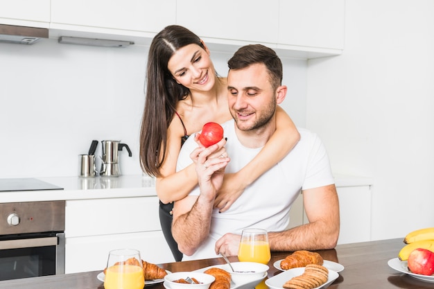 Loving jeune couple tenant la pomme dans la main tout en prenant son petit déjeuner