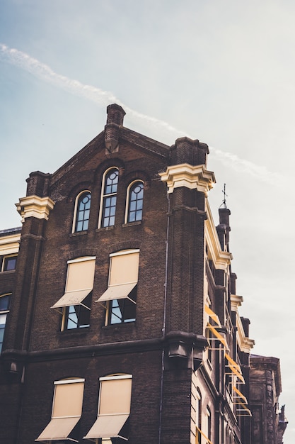 Photo gratuite low angle shot vertical d'un bâtiment brun et beige sous un ciel clair