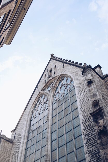 Low angle shot vertical d'un vieux bâtiment en brique sous le ciel nuageux