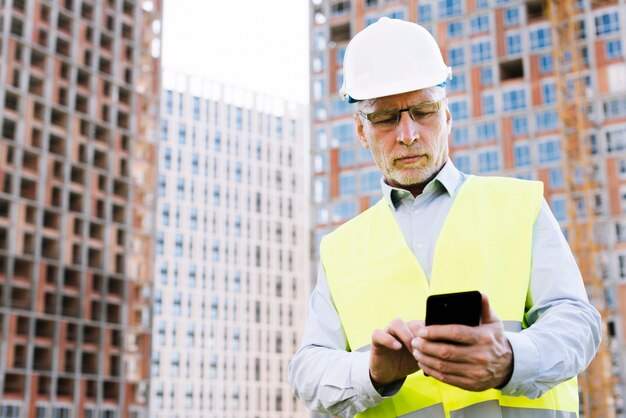 Low angle vieil homme regardant smartphone