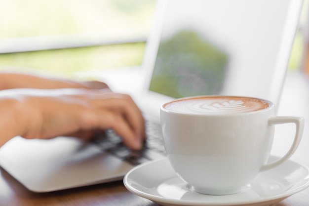 Lperson travaillant sur un ordinateur portable avec une tasse de café à côté