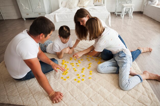 Ludique famille jouant au scrabble ensemble à la maison