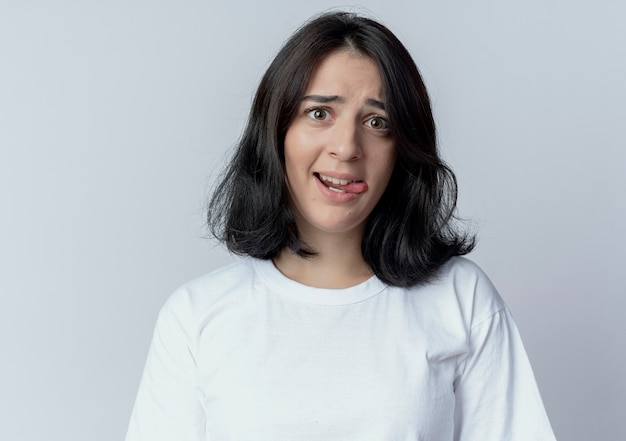 Ludique jeune jolie femme caucasienne montrant la langue regardant la caméra isolée sur blanc