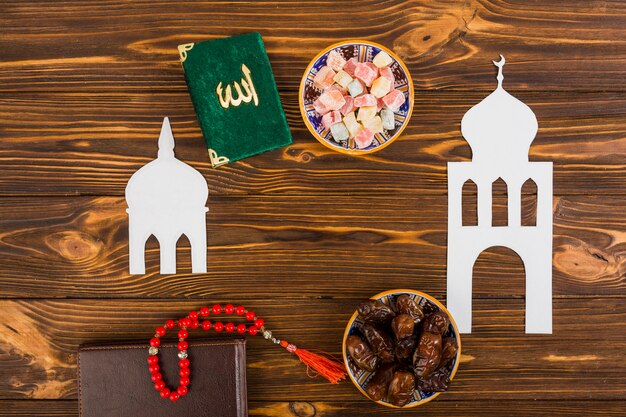 Lukum multicolore; livre de kuran; perles de prière et journal intime avec mosquée islamique blanche découpée sur un bureau en bois