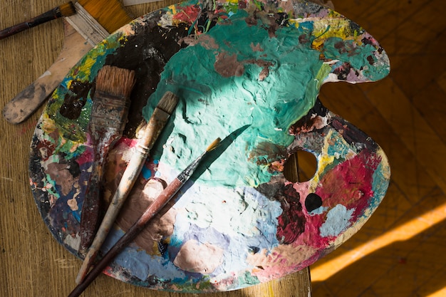 Lumière du soleil sur la palette en désordre et brosse sur la table en bois