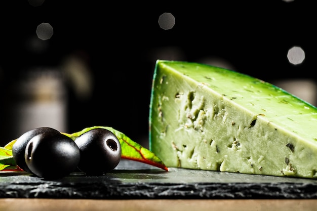 La lumière illumine la plaque noire avec du fromage vert et des olives