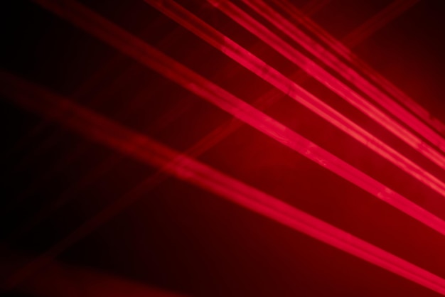 Les lumières laser au néon rouge vif illuminent l'obscurité en créant des lignes et des formes triangulaires dans un effet de science-fiction.