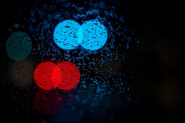 Lumières de voiture floues sur les fenêtres humides