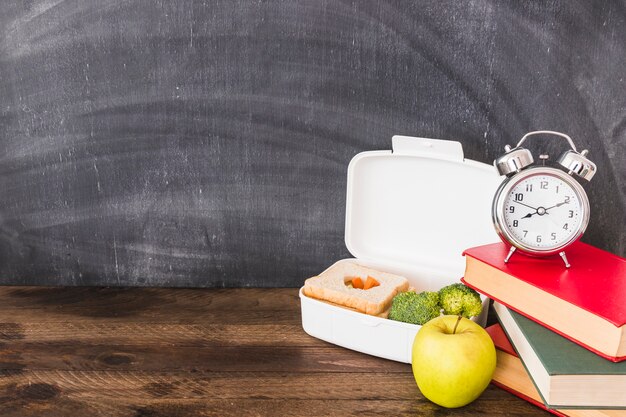 Lunchbox et apple près de livres et réveil