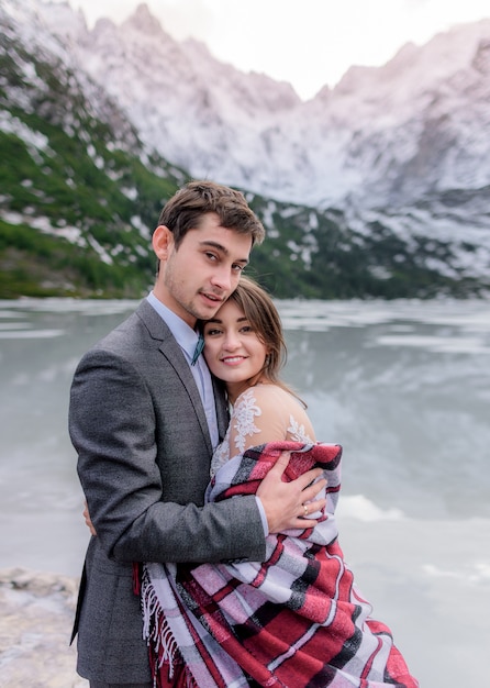 Lune de miel de rêve d'un couple juste marié amoureux dans les montagnes d'hiver et le pittoresque lac gelé