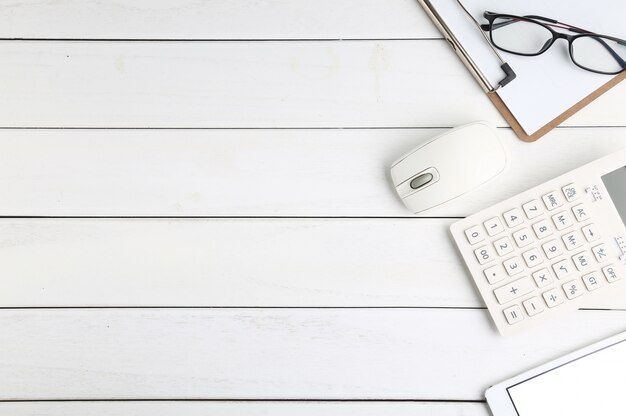 Lunettes, calculatrice et tablette sur bureau blanc et soigné