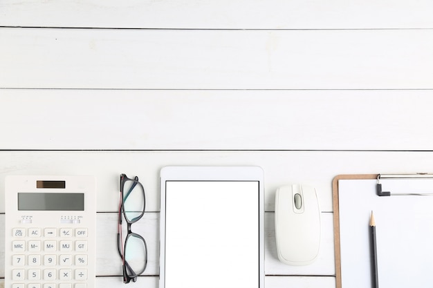 Lunettes, calculatrice et tablette sur bureau blanc et soigné