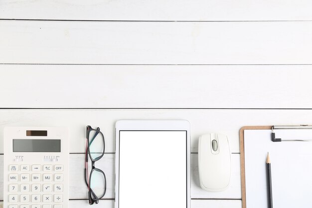 Lunettes, calculatrice et tablette sur bureau blanc et soigné