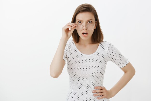 Lunettes de décollage femme choquée et regardant de plus près avec visage confus