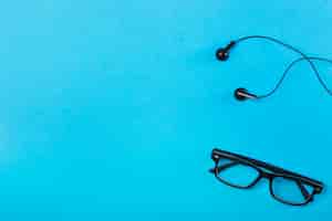 Photo gratuite lunettes noires et écouteurs sur fond bleu