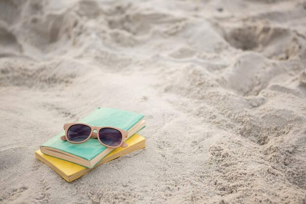 Lunettes de soleil et des livres sur le sable