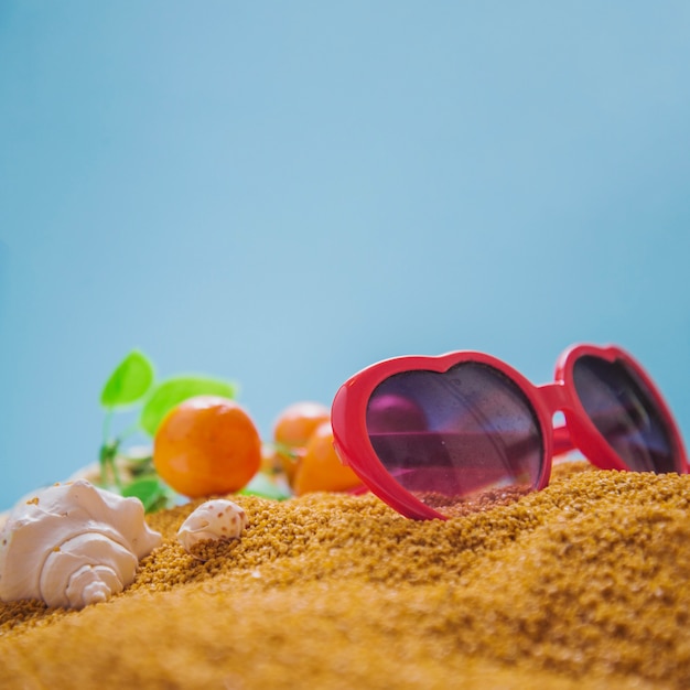 Lunettes de soleil et oranges sur sable