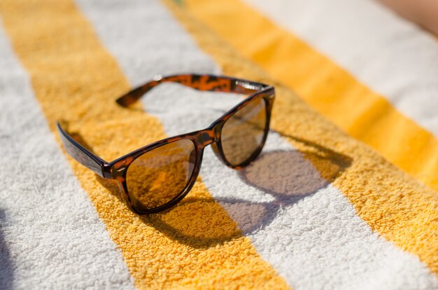 Lunettes de soleil sur serviette de plage jaune