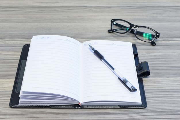 Lunettes, stylo et agenda ouvert sur le bureau