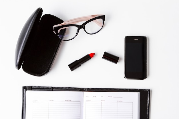 Lunettes de téléphone rouge à lèvres et ordinateur portable sur la surface blanche ci-dessus.