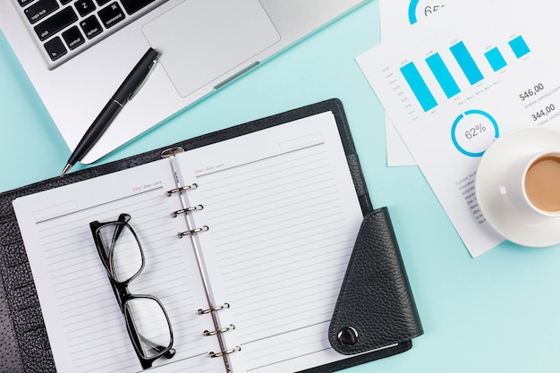 Lunettes de vue sur agenda, ordinateur portable, stylo, tasse à café et plan budgétaire sur le bureau