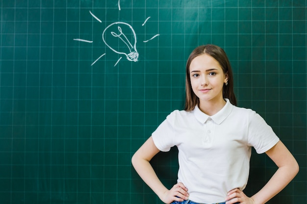 Photo gratuite lust bulbe sur le tableau noir et étudiant posant